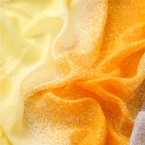 Macro detail of yellow and orange gradient scarf fabric with delicate white speckle texture