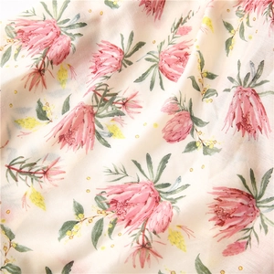 Detailed close-up of soft floral fabric featuring pink protea flowers and green leaves