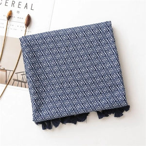Détail d'une écharpe en coton à fleurs bleues avec des franges à pompons