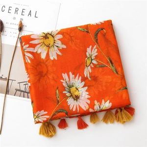 Detail of light cotton linen scarf with daisy print and orange yellow fringe tassels