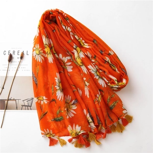 Orange floral cotton linen scarf with daisy print and tassel fringe on a bright background