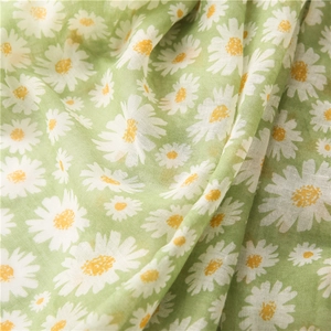 Détail d'une écharpe en coton et lin vert clair avec imprimé floral de marguerites