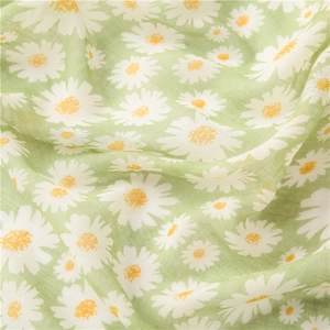 Gros plan d'une écharpe en coton et lin vert avec motif marguerites et texture du tissu