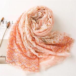 Détail du motif floral bohème sur châle orange clair avec finition à bords effilochés