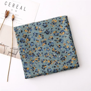 Detail of floral cotton linen scarf with frayed edges near a magazine and dried flowers