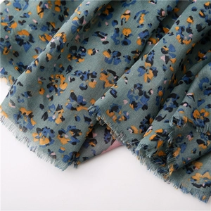 Detail of bohemian floral cotton linen scarf with frayed edges in grey-green and orange