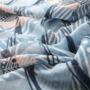 Détail macro d'une écharpe en coton et lin avec plumes bleues et motifs abstraits
