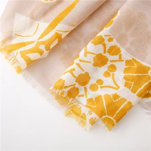 Macro shot of ginger yellow floral print fabric with natural raw fringe edges on cotton scarf