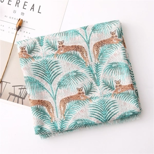 Detailed view of tropical leopard print scarf with fringe edges on a white table