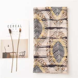 Détail d'une écharpe légère en coton et lin avec des motifs de feuilles géométriques