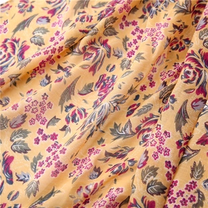 Detail of floral printed fabric showing yellow cotton-linen texture with pink flowers