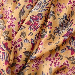 Detail of yellow cotton-linen scarf with red floral prints and delicate fringe edges