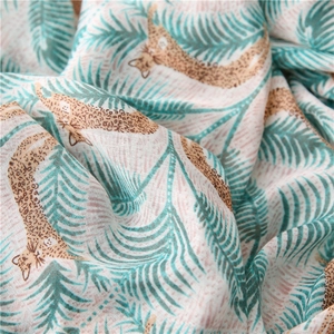 Detailed macro view of leopard print and green tropical palm leaf on linen cotton shawl