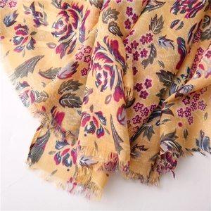 Detailed close-up of floral print cotton scarf with yellow base and fringe edges