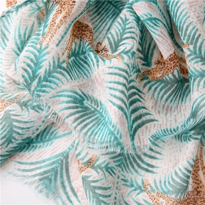 Detail of leopard and tropical palm leaf print on cotton scarf with fringe edges
