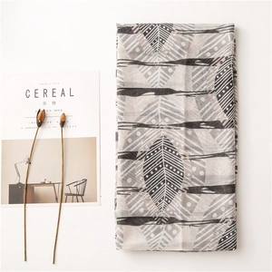 Détail d'une écharpe légère en coton avec motifs de feuilles géométriques et rayures
