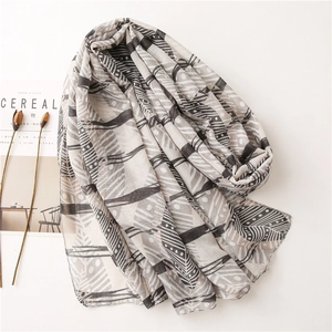 Détail du motif feuille géométrique gris et beige sur une écharpe légère en coton et lin