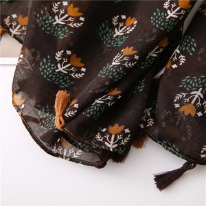 Close-up of lightweight linen scarf featuring orange floral prints and tassel details
