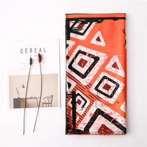 Écharpe orange et noire à motif géométrique avec bords effilochés sur fond blanc