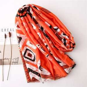 Écharpe orange avec motifs géométriques et franges sur un bureau au style épuré
