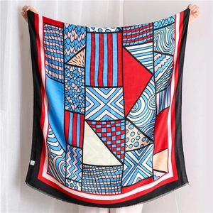 Close-up of geometric pattern scarf with abstract blue and red motifs and fine fringes
