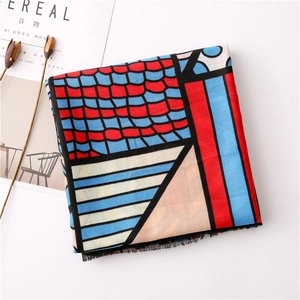 Detail of geometric scarf with red scales and blue stripes featuring fringed edges