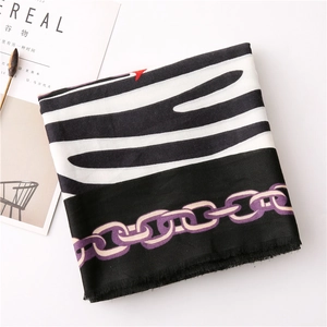 Detail of zebra pattern and chain print scarf with frayed edges on a white background
