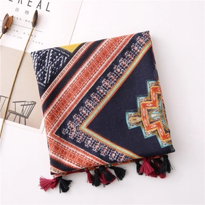 Détail du foulard à imprimé géométrique avec des pompons à franges rouge et noir