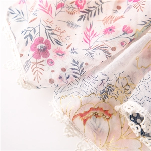 Detail of floral scarf featuring white crochet lace trim and elegant gold foil accents