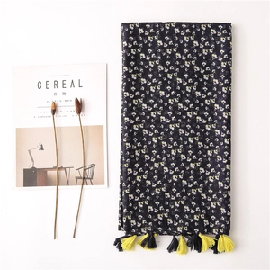 Navy floral cotton linen scarf with tassels shown next to lifestyle magazine and dried flowers