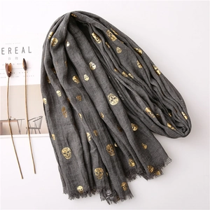Fashionable dark grey scarf with golden skull prints and fringed edges on white background