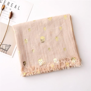Close-up of gold skull foil prints and frayed edges on lightweight cotton linen scarf
