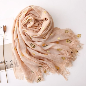Detail of pink cotton linen scarf with gold foil skull patterns and fringe edges