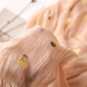 Macro detail of pink scarf showing gold foil skull pattern and linen texture