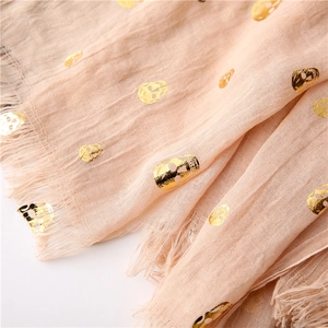 Detail of pink scarf showing gold foil skull patterns and raw fringe edge texture