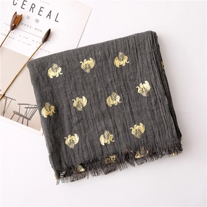Close-up of charcoal grey scarf with gold elephant prints and tassel edges on cotton linen
