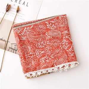 Detail of orange paisley cotton scarf with delicate white floral lace trim and soft texture