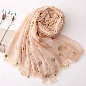 Close-up of gold foil elephant patterns and frayed fringe on apricot cotton scarf