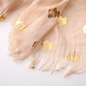 Detail of light beige scarf showing golden elephant print and frayed tassel edges
