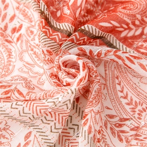 Close-up of paisley cotton linen scarf featuring orange patterns and silver sequins