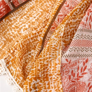Detail of bohemian scarf featuring paisley patterns, sequins, and white lace trim edge