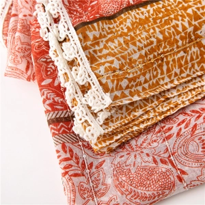Detail of cotton linen scarf with red paisley print, sequins and white lace trim