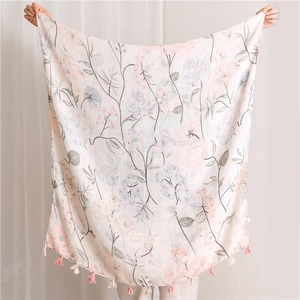 Detail of floral linen scarf with pink blossoms and delicate tassel edges in soft beige