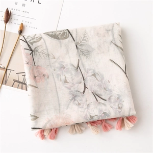 Detail of floral print linen scarf with pink fringe tassels on a white background