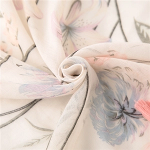 Detailed close-up of cotton linen scarf with floral print and pink tassel fringe