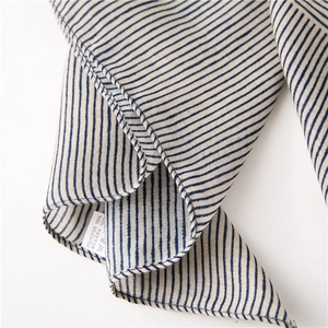 Detail view of blue and white striped scarf showing 100% polyester texture and fine stitching