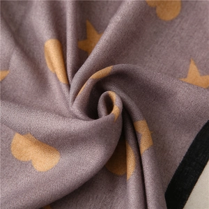Detailed close-up of dark mauve scarf fabric with golden star and heart patterns