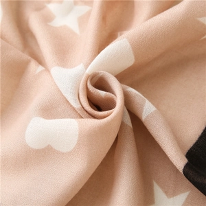 Detail of light brown scarf with white star patterns and soft woven fabric texture