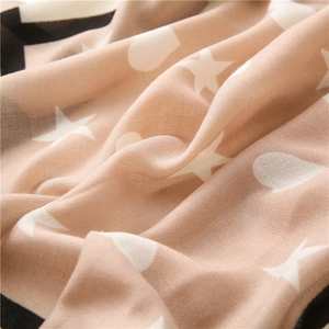 Detail of soft beige scarf with white heart prints and black contrasting border