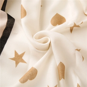 Detail of soft off-white scarf fabric with delicate gold heart and star patterns